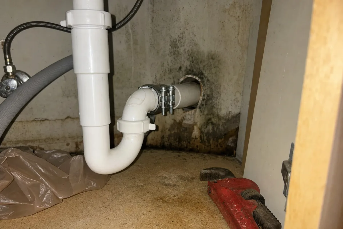 A repaired pipe beside old mold staining.