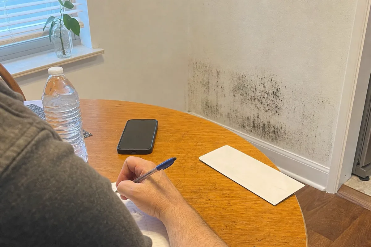 A homeowner writes questions beside a visible mold patch.